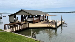 Une plateforme flottante dotée d’un espace de couchage abrité, d’une petite terrasse et d’une zone herbeuse adjacente à l’eau.