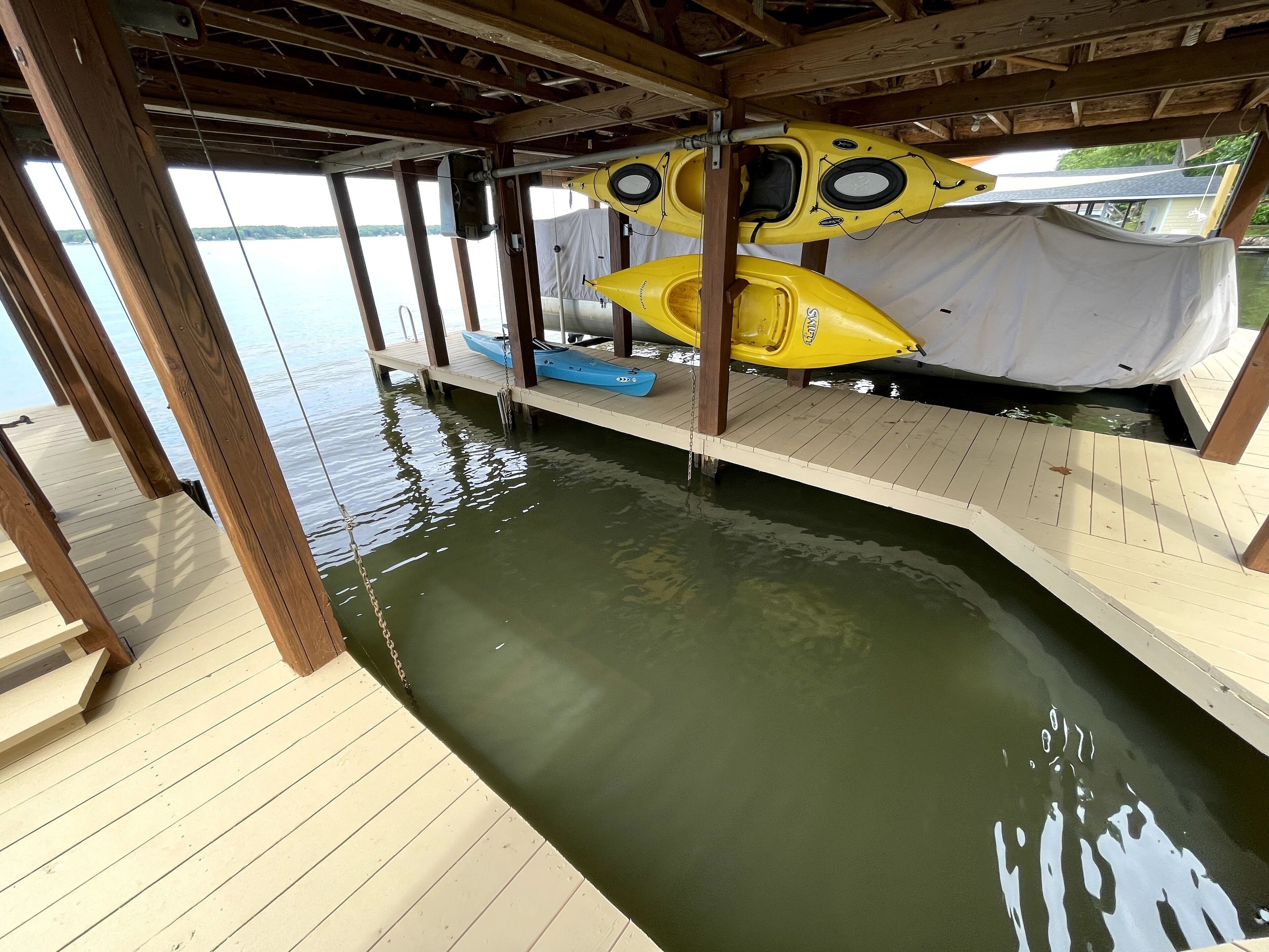 A wooden dock with kayaks and a covered area.