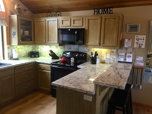 Enjoy cooking in this well-equipped kitchen with a stove, microwave, sink, and ample storage.
