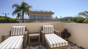 A balcony with wicker furniture and a potted plant.
