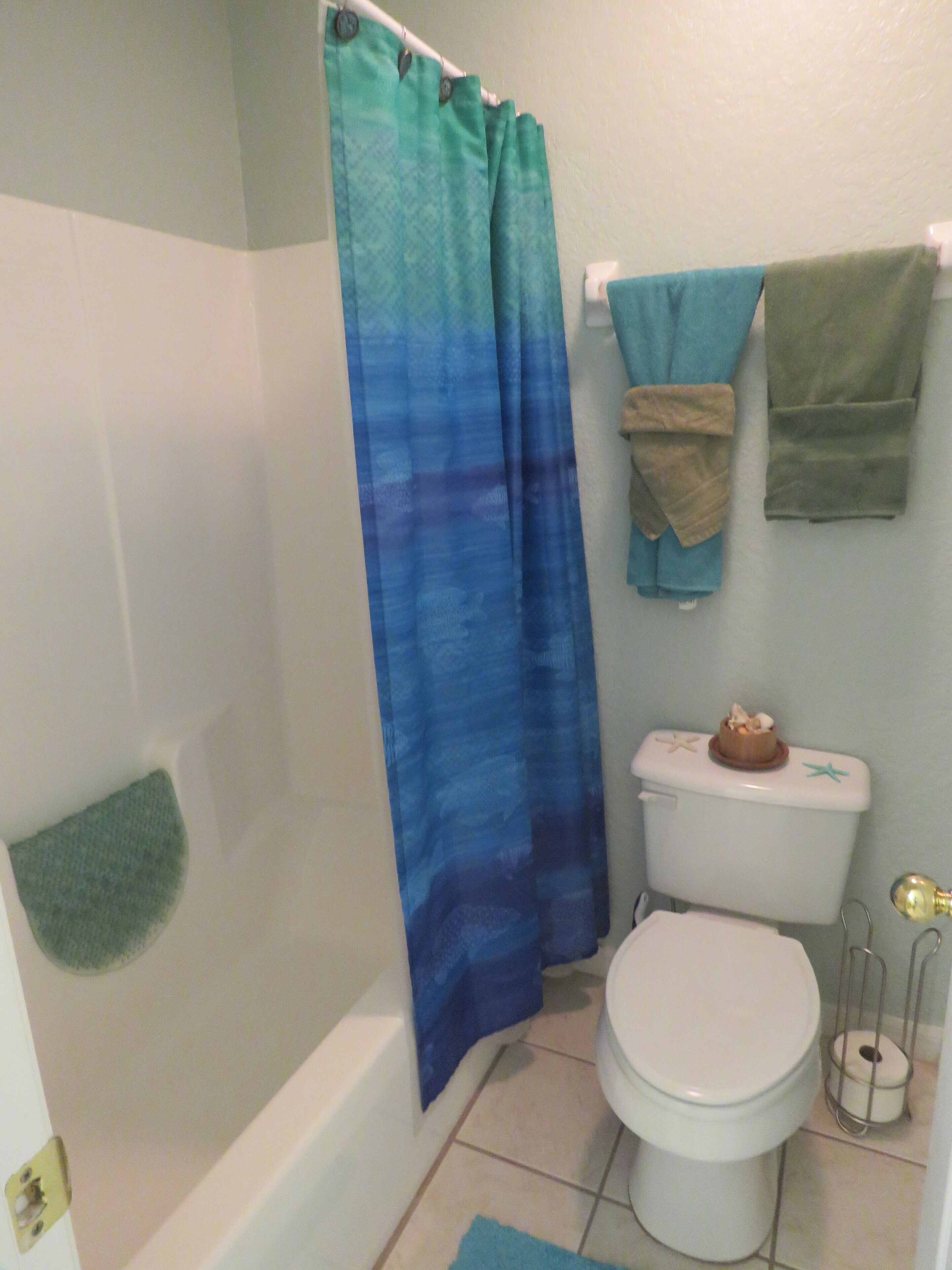 A bathroom with a bathtub, toilet, and shower curtain.