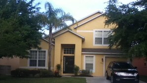 A two-story yellow house with a black car parked in the driveway. - 5 Star - 5 BR/4 Bath Villa - Perfect for Family vacation. Minutes to Disney. (Clermont)