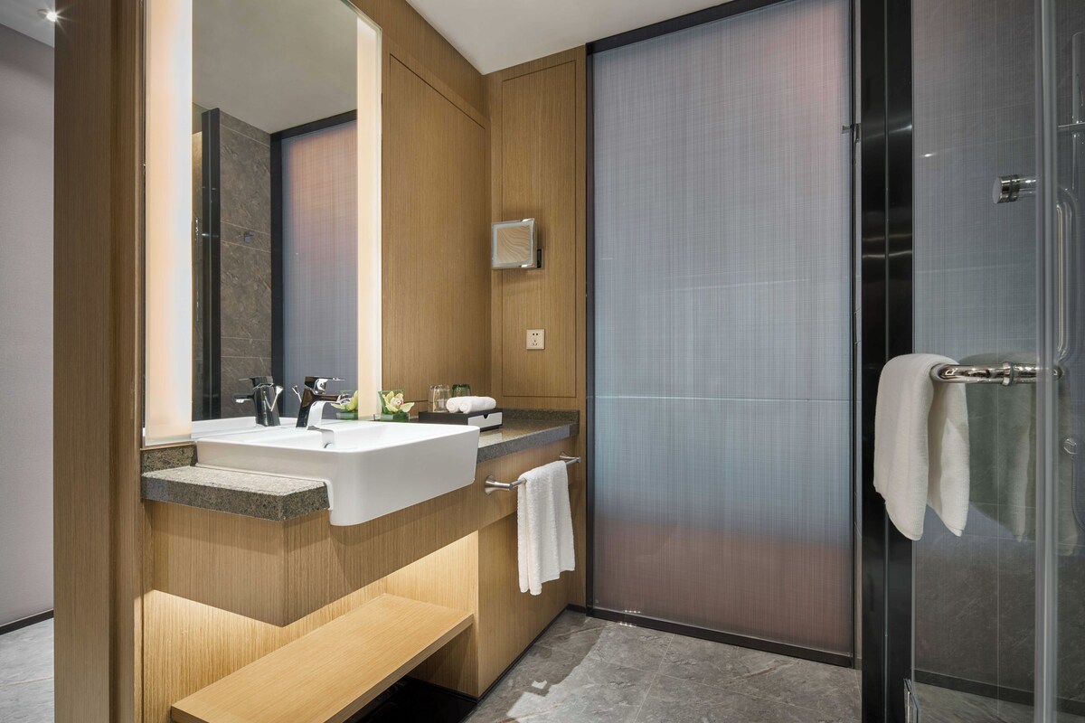 Une salle de bain moderne avec un meuble-lavabo en bois, deux vasques, une douche en verre et un grand miroir.