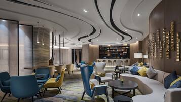Un moderno hall de hotel con zonas de estar, un bar y una estantería.