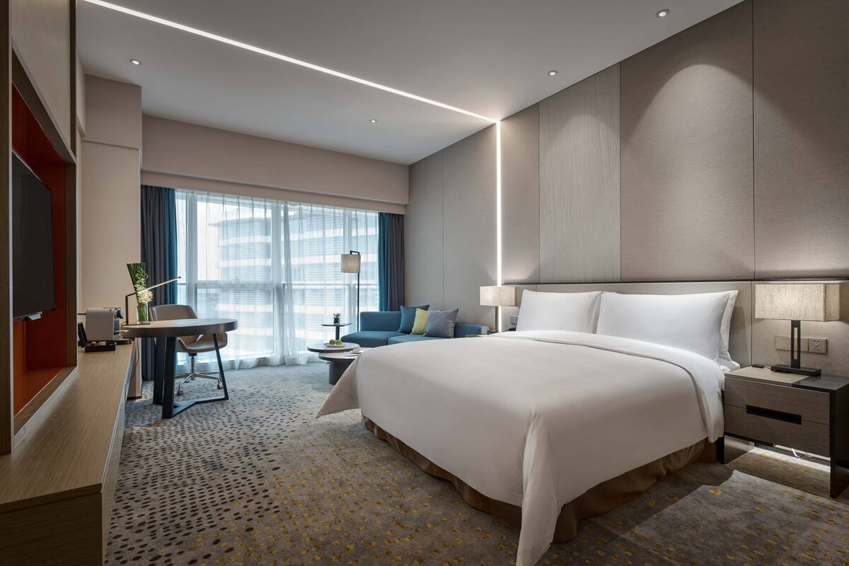 Een moderne hotelkamer met een groot bed, een bureau, een slaapbank en een televisie.