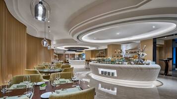 A modern dining area with round tables, chairs, and a central buffet.