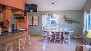 A kitchen with a bar area, wooden chairs, and a dining table.