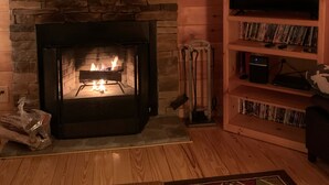 Una sala de estar acogedora con chimenea de piedra, estanterías de madera y un televisor.