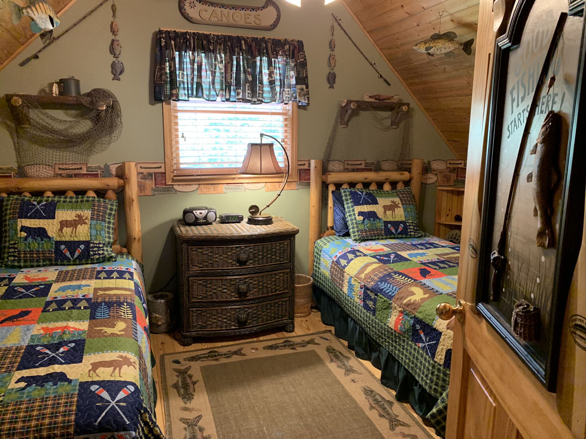 A cozy cabin with two beds, a wooden dresser, and fishing-themed decor.