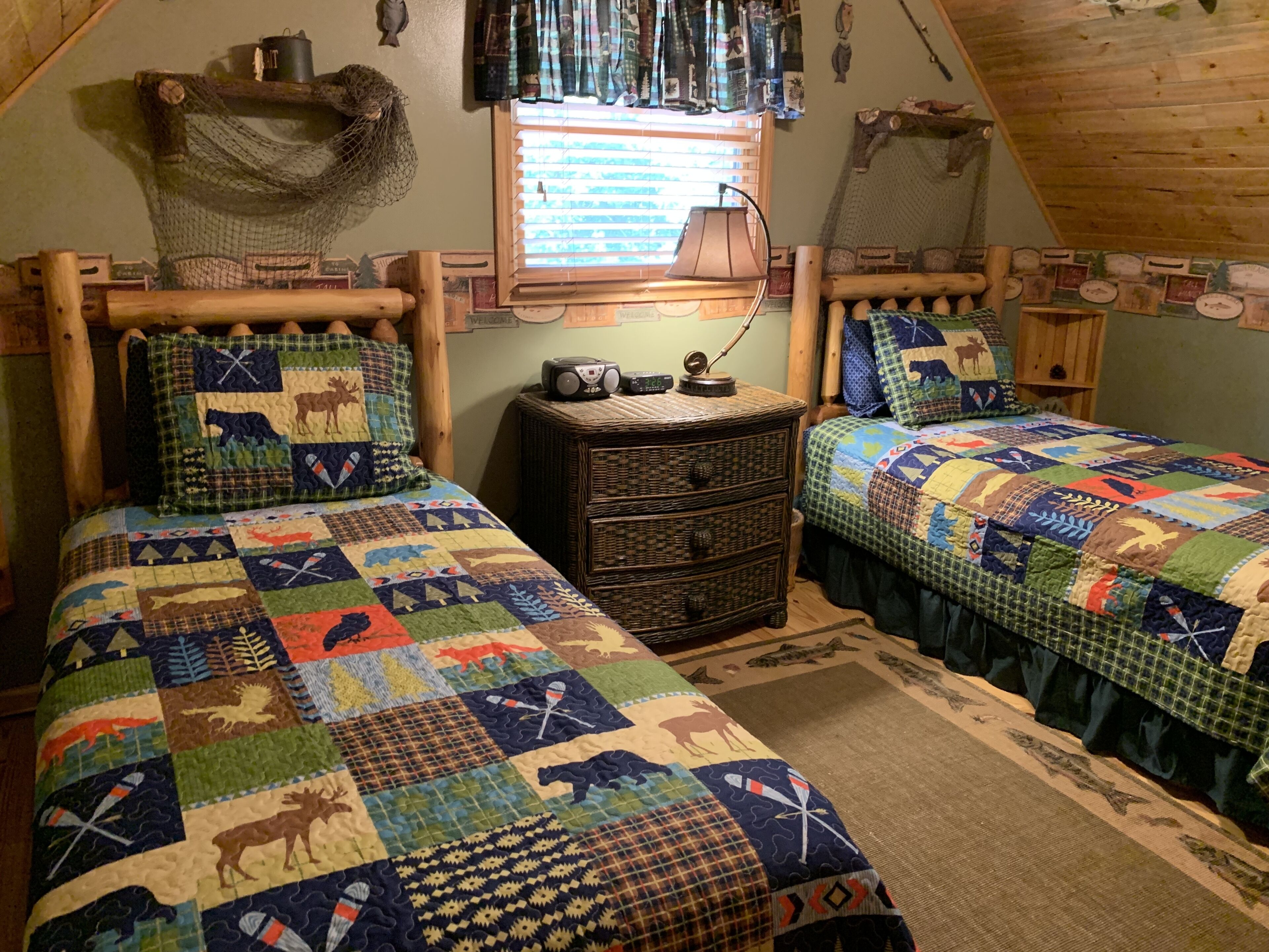 A cozy room with two beds, a wooden dresser, and a window with blinds.