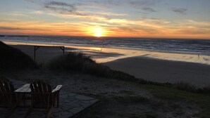 A beach with a sunset, chairs, and a wooden structure.