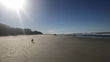 A wide beach with footprints and a person walking.