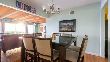 A dining area with a glass-top table, wooden chairs, and a chandelier.