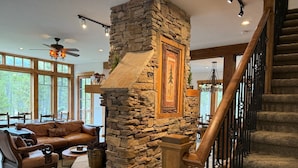 Un salón acogedor con chimenea de piedra, una escalera de madera y un sofá de cuero.