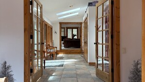Un pasillo con puertas de madera, un candelabro y una alfombra.