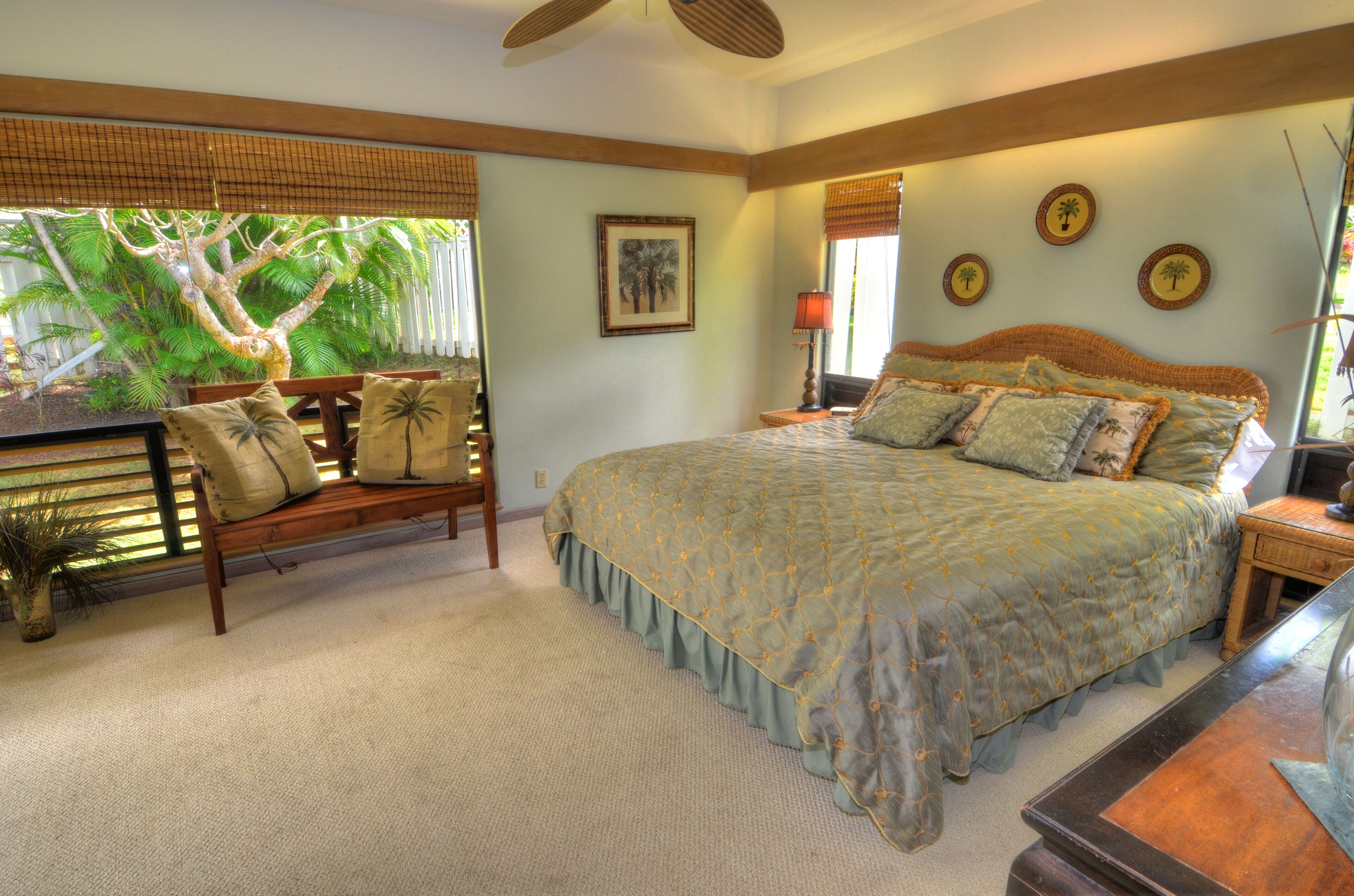 A bedroom with a bed, a bench, a nightstand, and a potted plant.