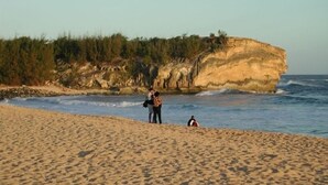 A sandy beach with a rocky cliff in the background. - PRIVATE HOME: 5 Min Walk to Beach, Pool & Tennis Courts (Koloa)