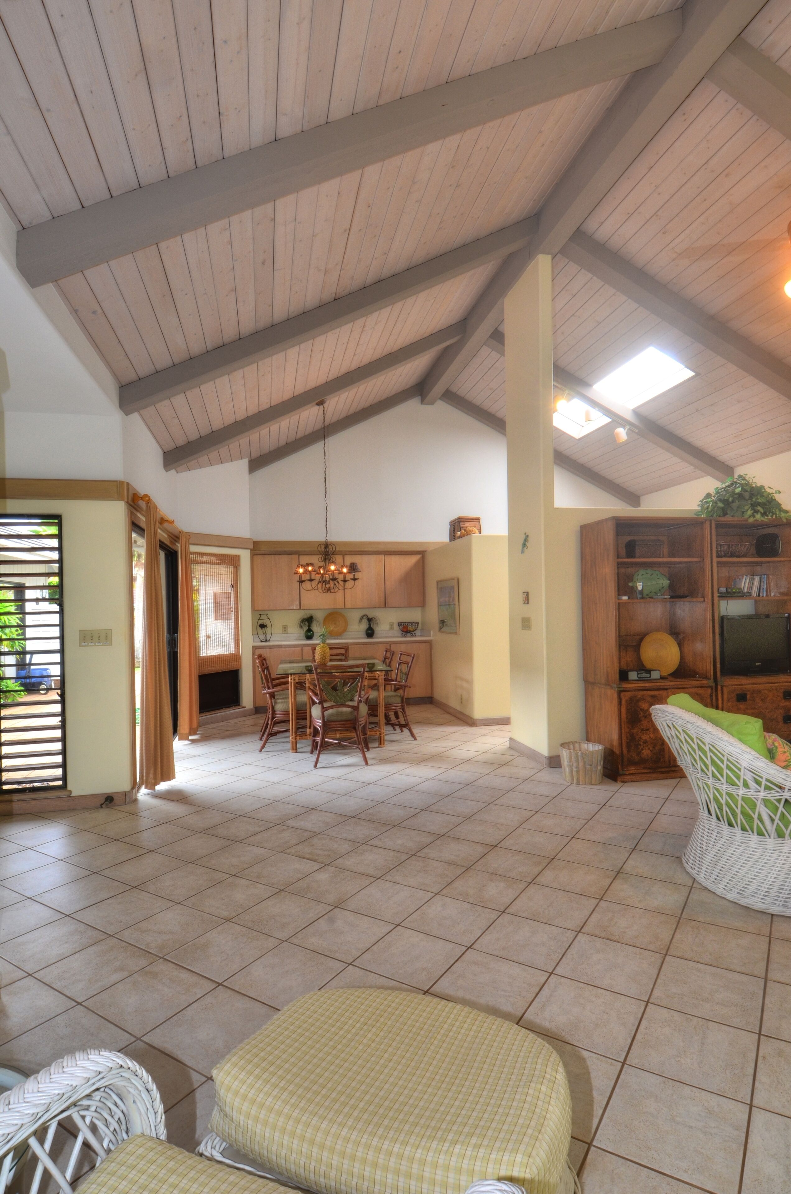 A spacious living area with a high ceiling, a dining table, and a seating area with cushions.