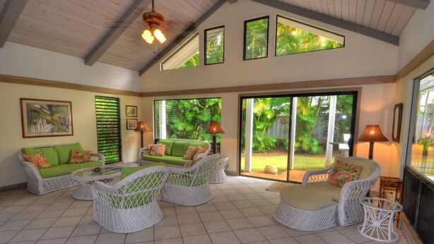 A spacious patio with wicker furniture, large windows, and a view of lush greenery. - PRIVATE HOME: 5 Min Walk to Beach, Pool & Tennis Courts (Koloa)