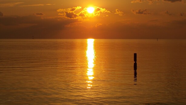 A sunset over a calm sea with a buoy in the foreground. - A Short Walk to Dauphin Island Beach.*Pets Welcome* 
special rates 20% Discount  (Dauphin Island)
