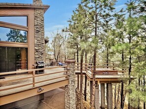 A modern cabin with a stone exterior, wooden deck, and a view of surrounding pine trees. - Timberloft Luxury Lodge, HOT TUB , GOLF COURSE views, secluded & private (Flagstaff)