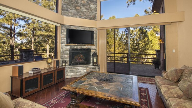 Un salón espacioso con chimenea de piedra, ventanas amplias y un área de estar confortable.