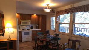 A kitchen with wooden cabinets, a stove, and a dining table with chairs.
