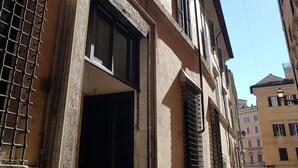 A building with multiple windows, some with shutters, and a visible door. - Residenza Sinibaldi - XVI century experience (Rome)