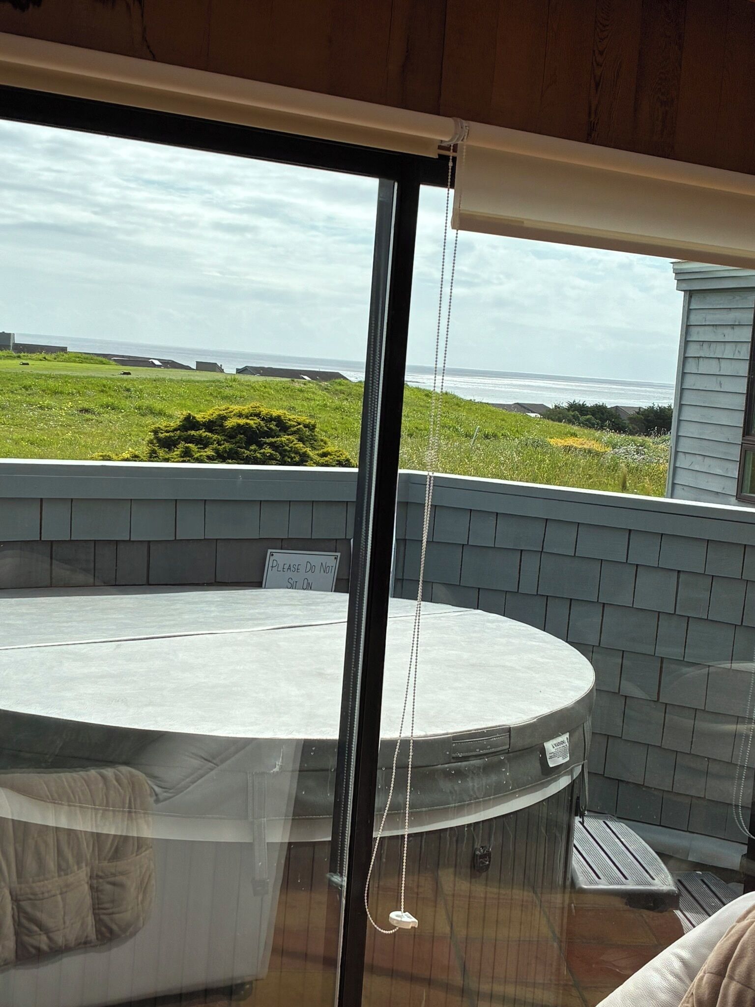 Un jacuzzi sur un balcon avec vue sur l’océan et un panneau indiquant : « VEUILLEZ NE PAS S’ASSEOIR ICI ».
