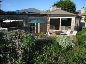 Une maison avec un patio, un parasol vert et une piscine.