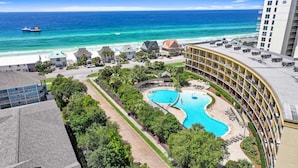 A resort with a large pool, beachfront view, and a building with balconies overlooking the pool. - Beach Resort 215 Beach Setup included* HUGE value added.  Perfect Pool View. Convenient Access (Miramar Beach)