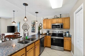 Enjoy cooking in the fully equipped kitchen with a granite countertop, stainless steel appliances, and wooden cabinets.