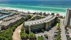 An aerial view of a coastal hotel with a parking lot, a beach, and ocean views. - Beach Resort 215 Beach Setup included* HUGE value added.  Perfect Pool View. Convenient Access (Miramar Beach)