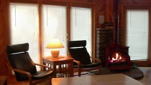 A cozy room with two leather chairs, a wooden table, a lamp, and a fireplace.