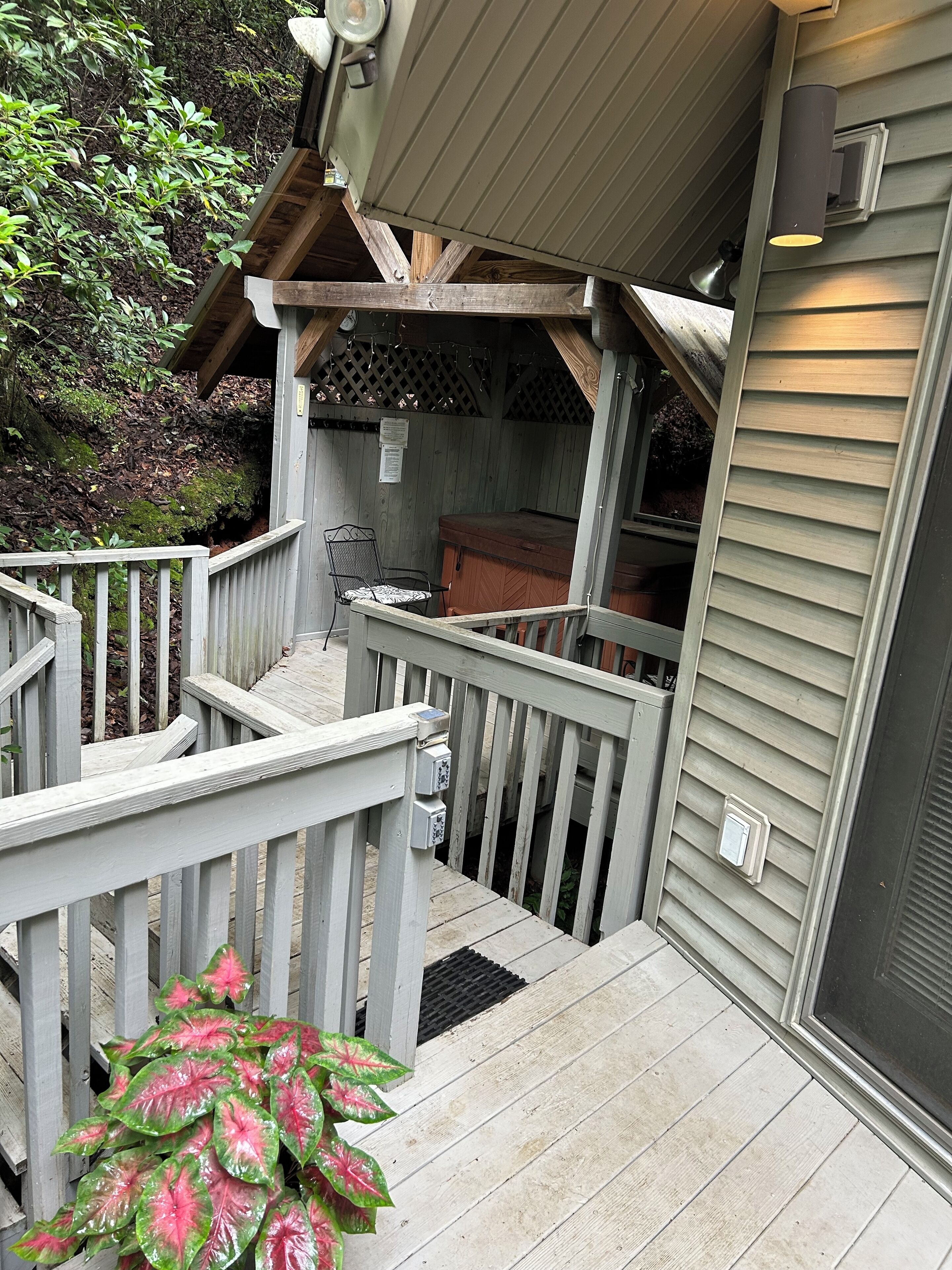 A wooden deck with a metal railing, a wooden bench, and a small wooden structure with a slanted roof.