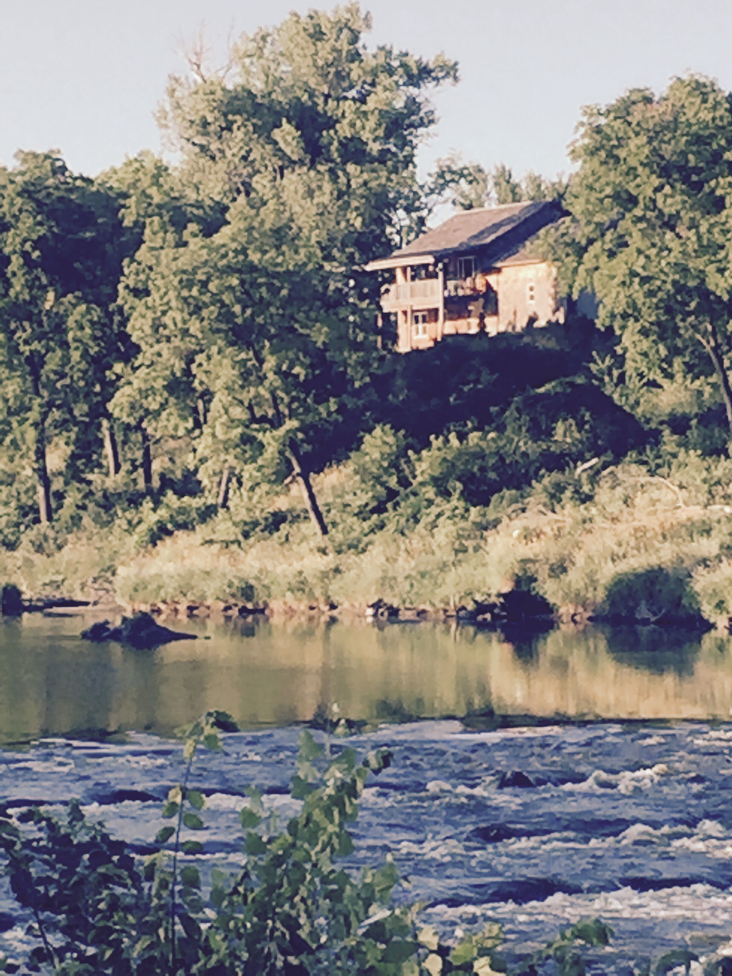Cabin on bluff of Big Sioux River with rushing waters of the Klondike Dam below.