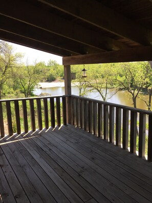 Une terrasse en bois avec une rambarde, donnant sur une rivière et une végétation luxuriante.