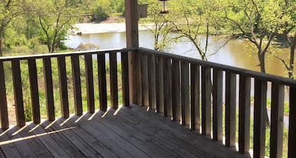 Cabin on bluff of Big Sioux River with rushing waters of the Klondike Dam below.