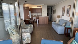 Una sala de estar moderna con sofá, sillas, una mesa de comedor y una zona de cocina.