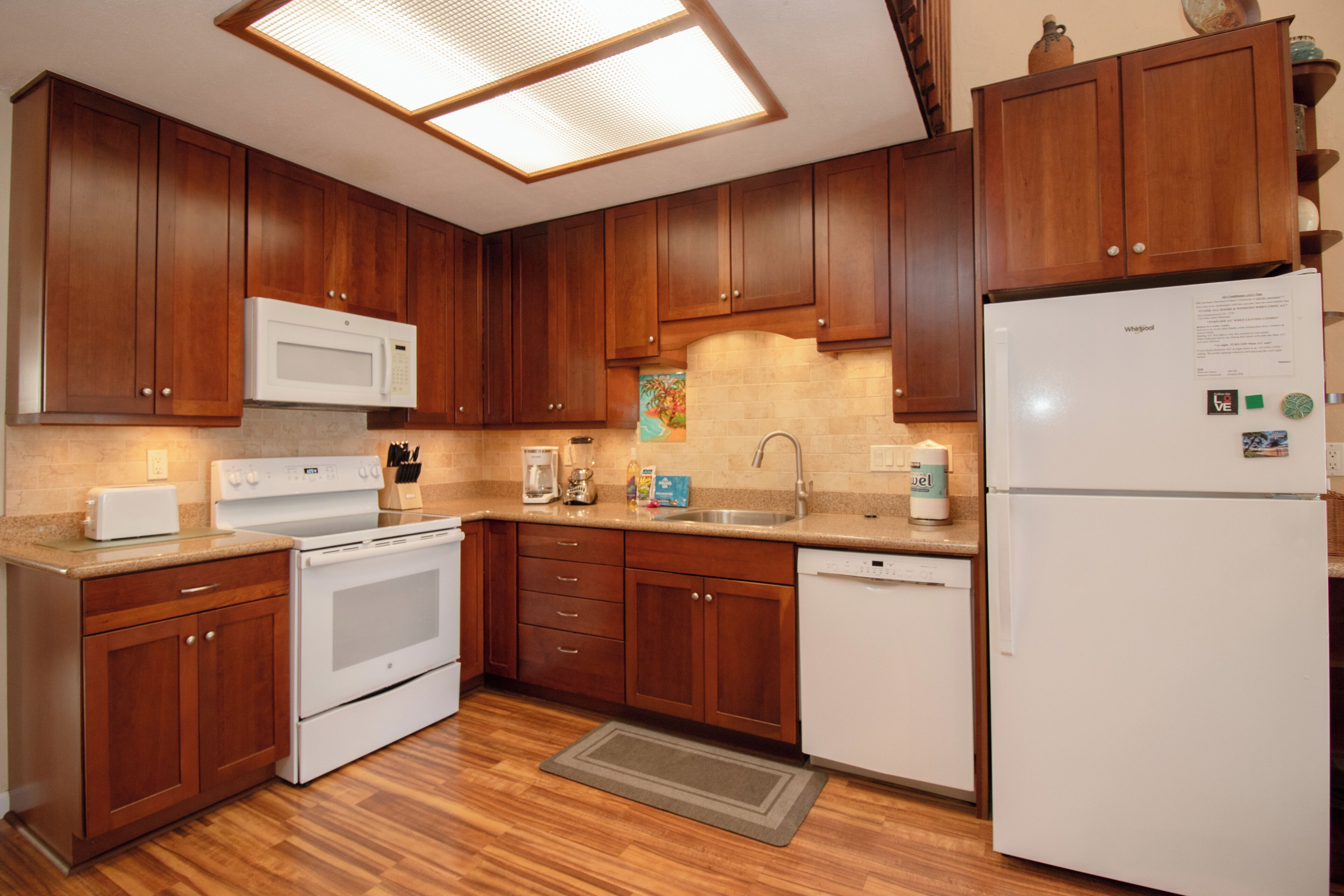 A kitchen with wooden cabinets, a white microwave, stove, and refrigerator.