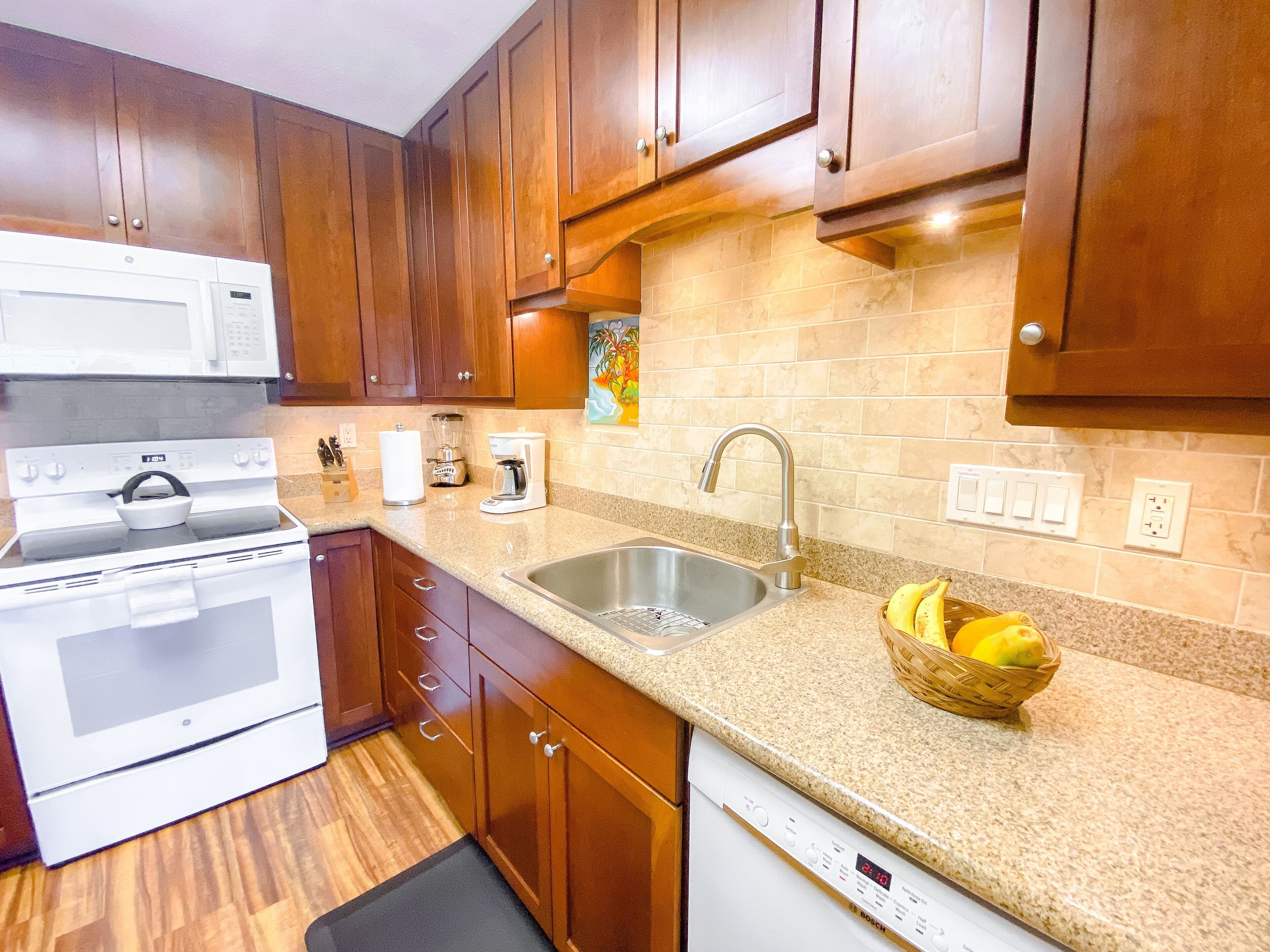 A kitchen with wooden cabinets, a white stove, a sink, and a dishwasher.