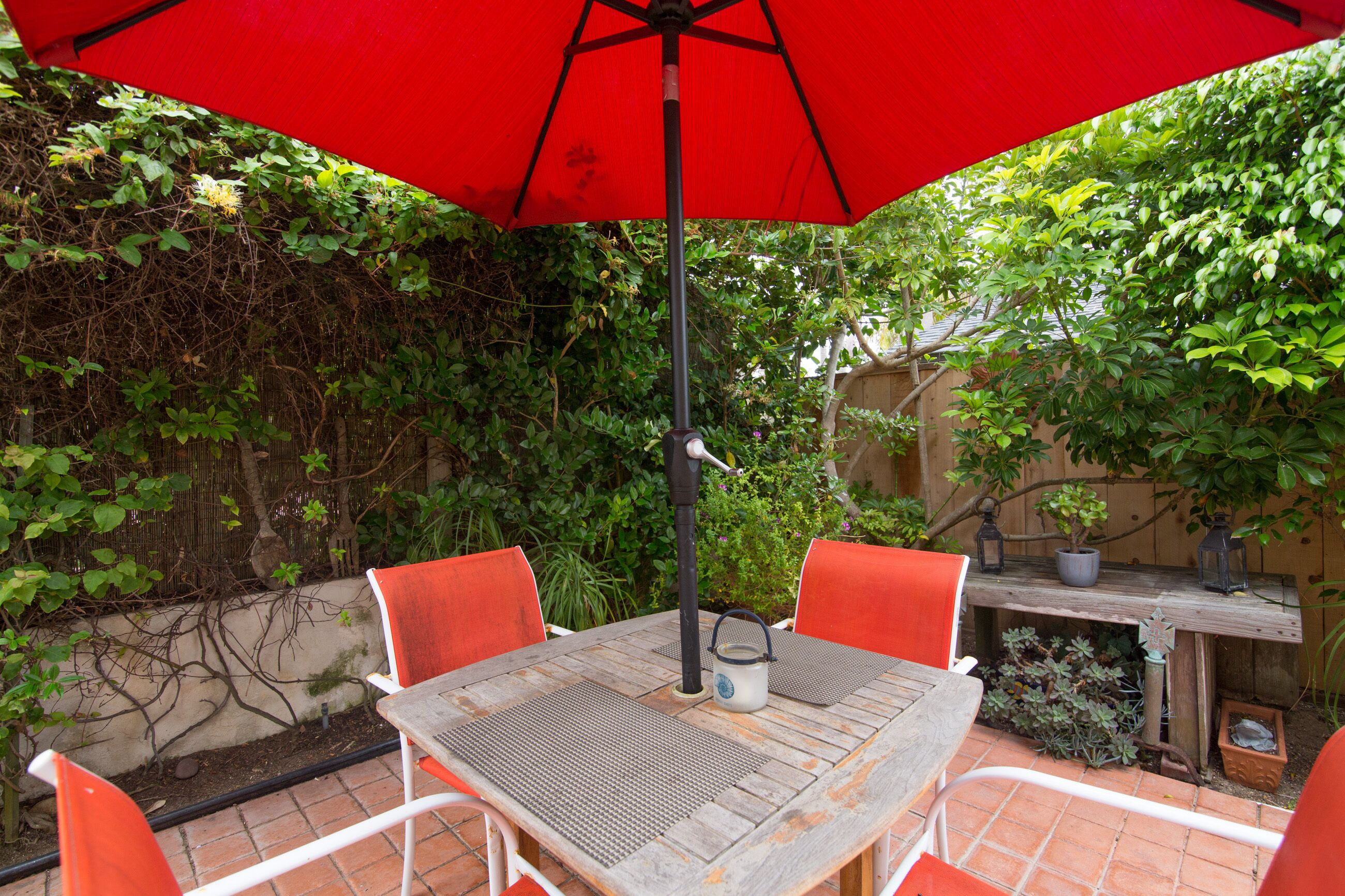 Una terrazza con tavolo e sedie, un ombrellone e un vaso con una pianta.
