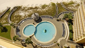 A circular pool area with two separate pools, surrounded by lounge chairs and palm trees. - Free parking til Nov. 15! 162 reviews, wrap around balcony, stay 7 pay for 6! OB (Orange Beach)