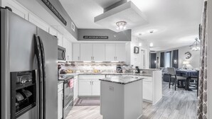 A modern kitchen with white cabinets, a built-in oven, and a central island. - Free parking til Nov. 15! 162 reviews, wrap around balcony, stay 7 pay for 6! OB (Orange Beach)