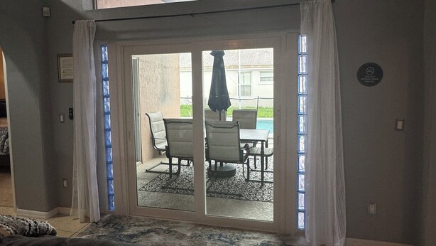 Ein Wohnzimmer mit einer großen Schiebeglastür, die zu einer Terrasse im Freien führt.
