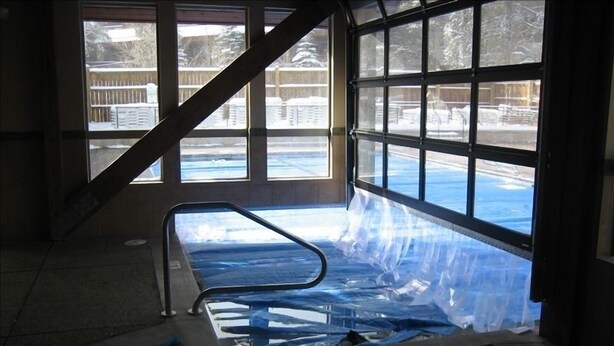 An indoor swimming pool with clear views of a snowy outdoor area through large windows.