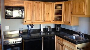 A compact kitchen with wooden cabinets, a stove, a dishwasher, and a sink.