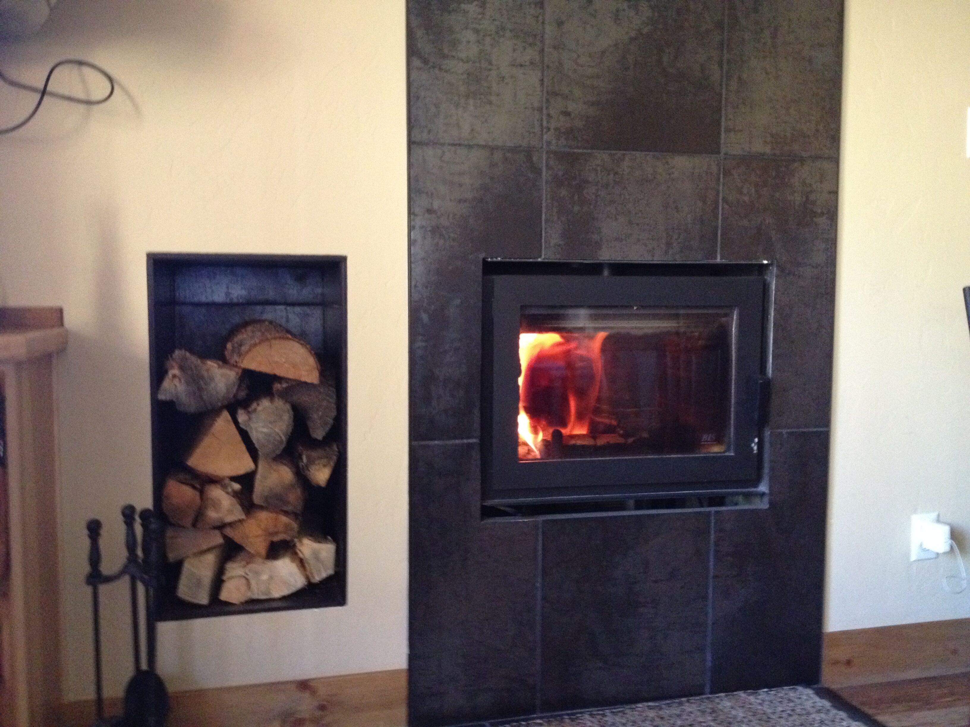 A fireplace with a stone surround and a fire burning inside.