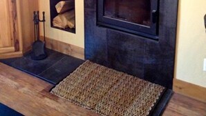 A modern living room with a stone fireplace, a flat-screen TV mounted on the wall, and a wooden cabinet.