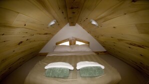A cozy, triangular wooden room with a bed, two pillows, and two bedside lamps. - Mountain View Chalet - Fantastic Views and Privacy  (Blackhawk)